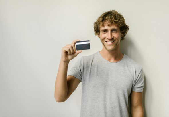 An international F-1 visa student holding a Deserve EDU Mastercard in front of a laptop showing a successful credit card approval screen.