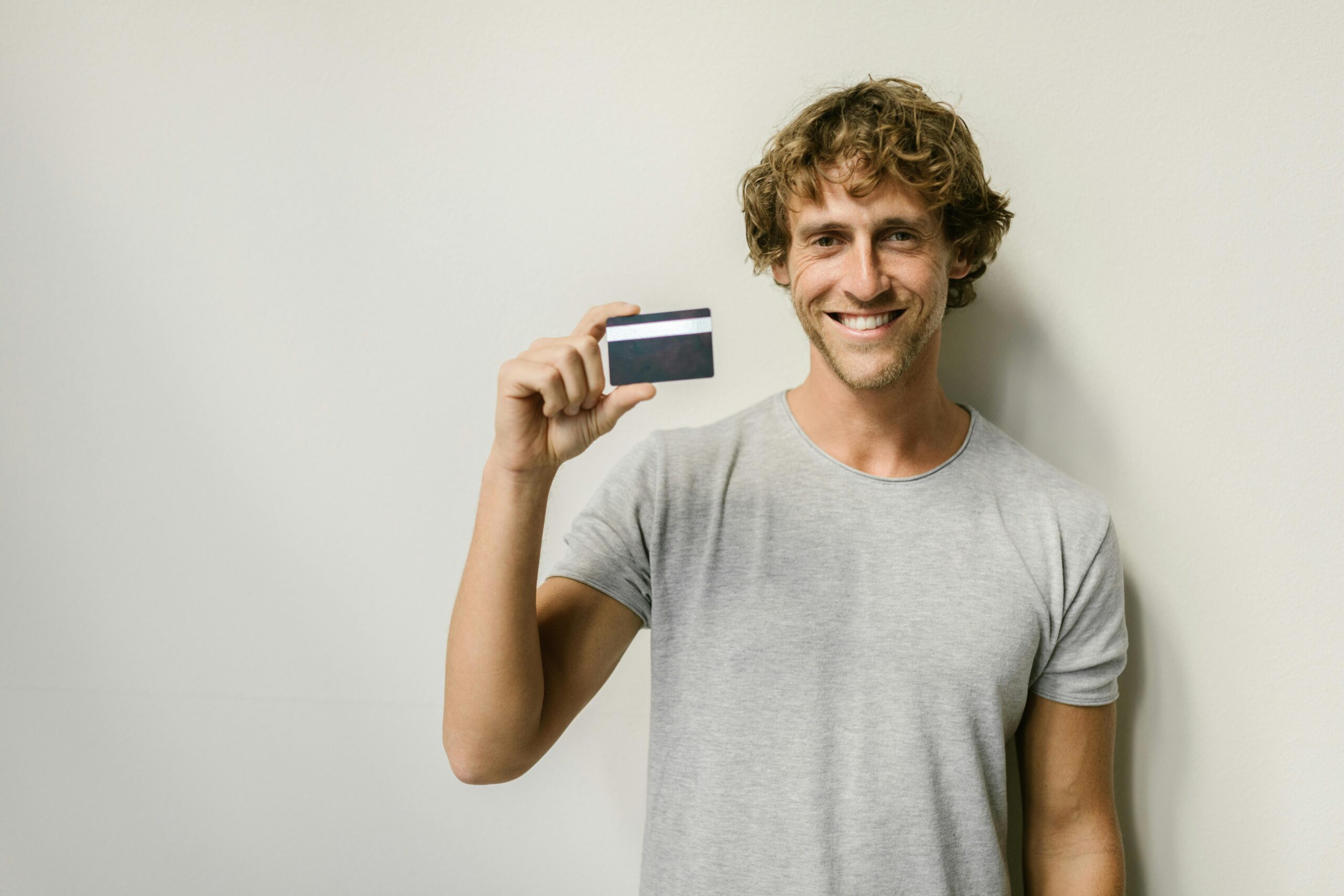 An international F-1 visa student holding a Deserve EDU Mastercard in front of a laptop showing a successful credit card approval screen.